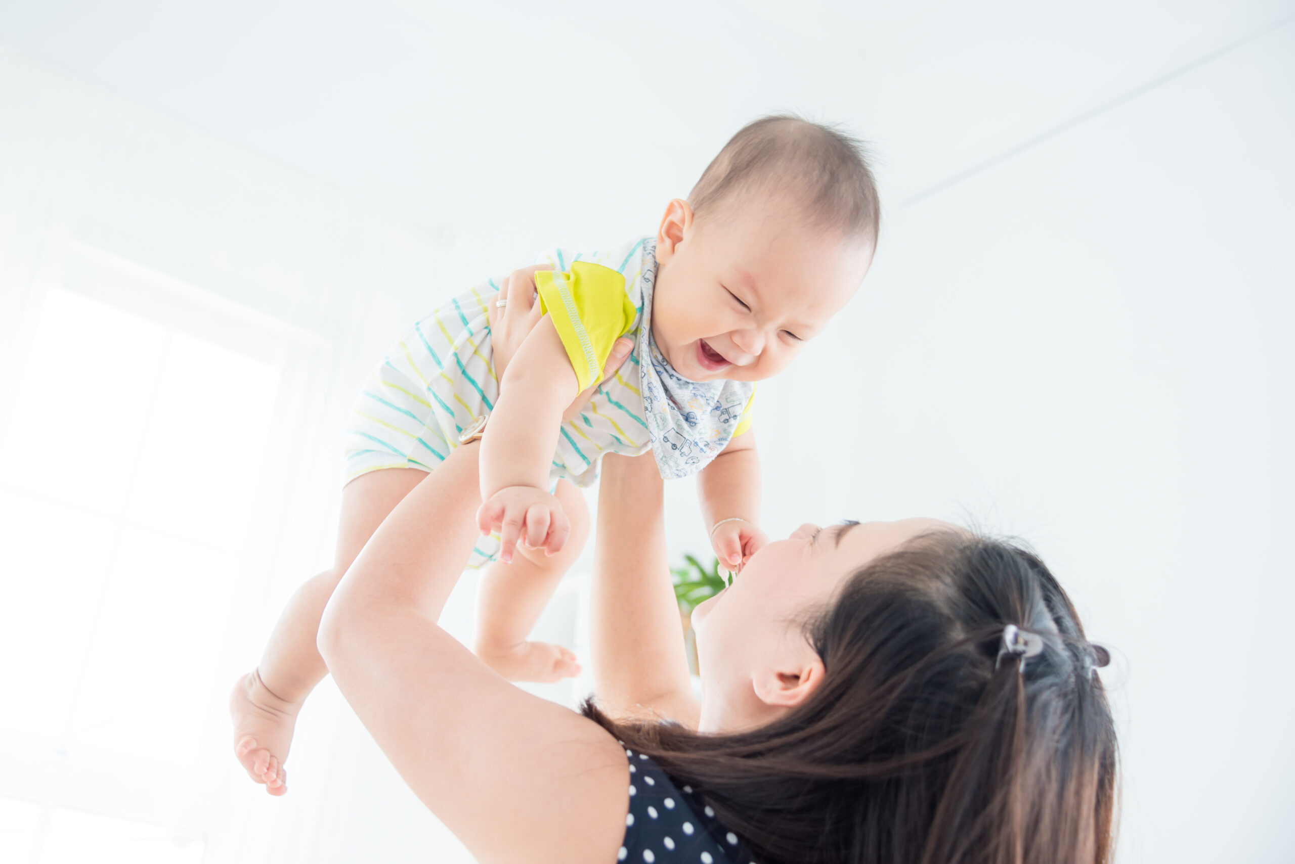 Little asian child smiles happily while playing with mother in living room